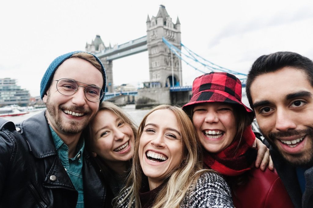 Happy friends having fun taking selfie with mobile phone in London - Focus on center girl face
