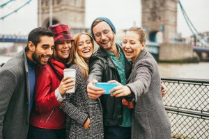 Happy friends having fun taking selfie with mobile phone in London with Tower Bridge in background
